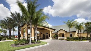 A hotel with a courtyard, palm trees, and a tiled roof.