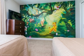 A bedroom with a jungle-themed mural, a TV on a dresser, and two beds. - Storey Lake - 3175 Pequod Place (Kissimmee)