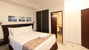 Een hotelkamer met een bed, een kledingkast en een badkamer, zichtbaar door een geopende deur.