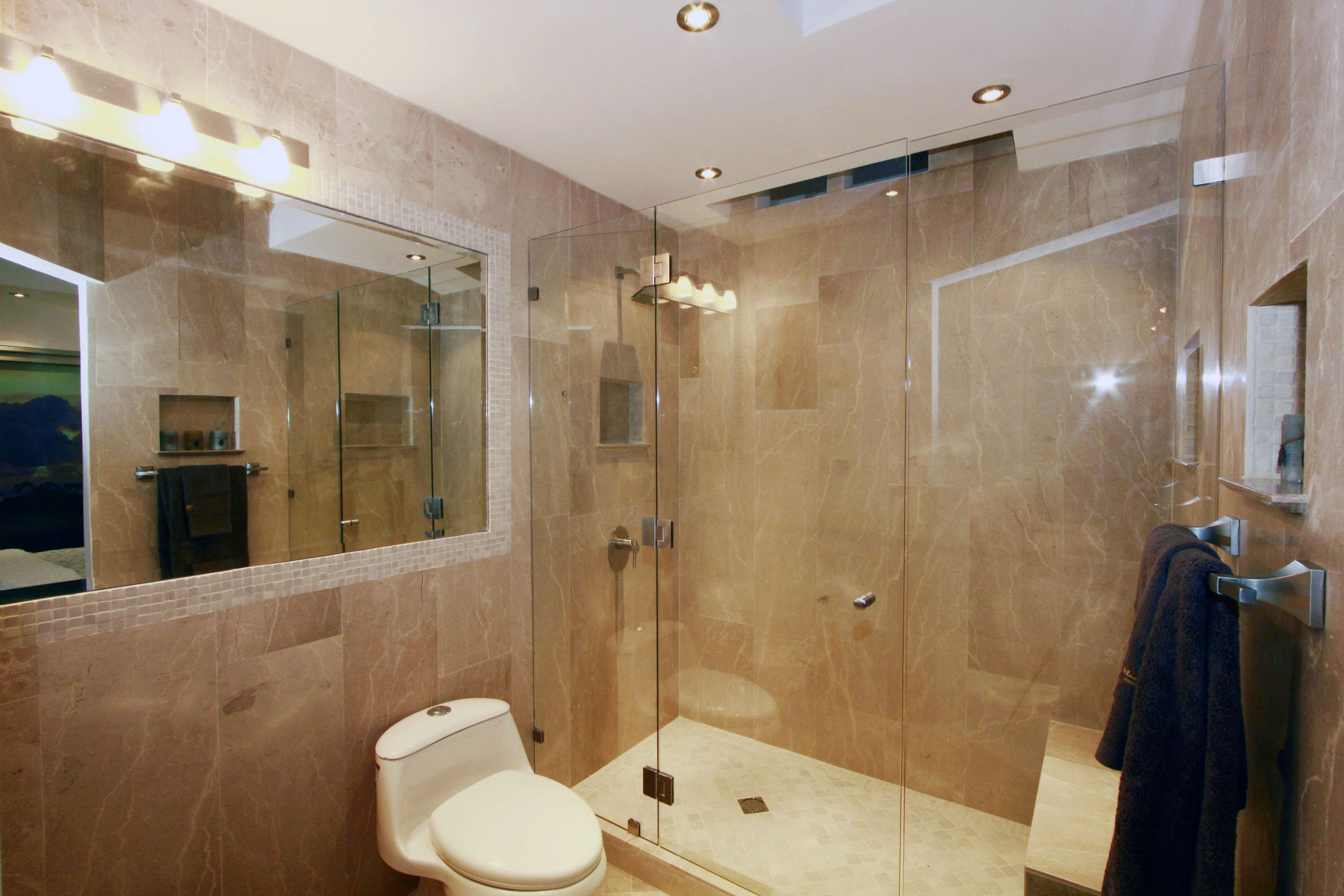 Een moderne badkamer met een douchecabine van glas, een toilet en een grote spiegel.
