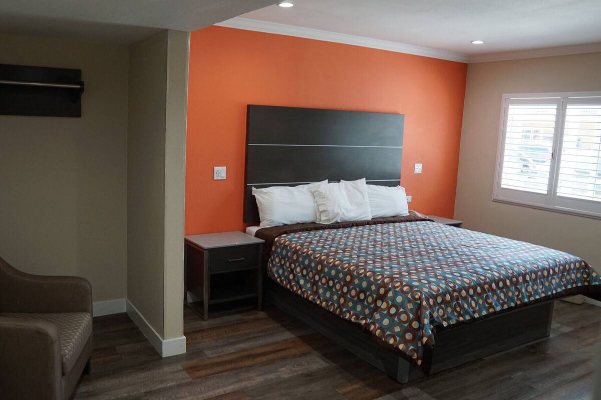 Een slaapkamer met een bed, nachtkastjes, een stoel en een raam.