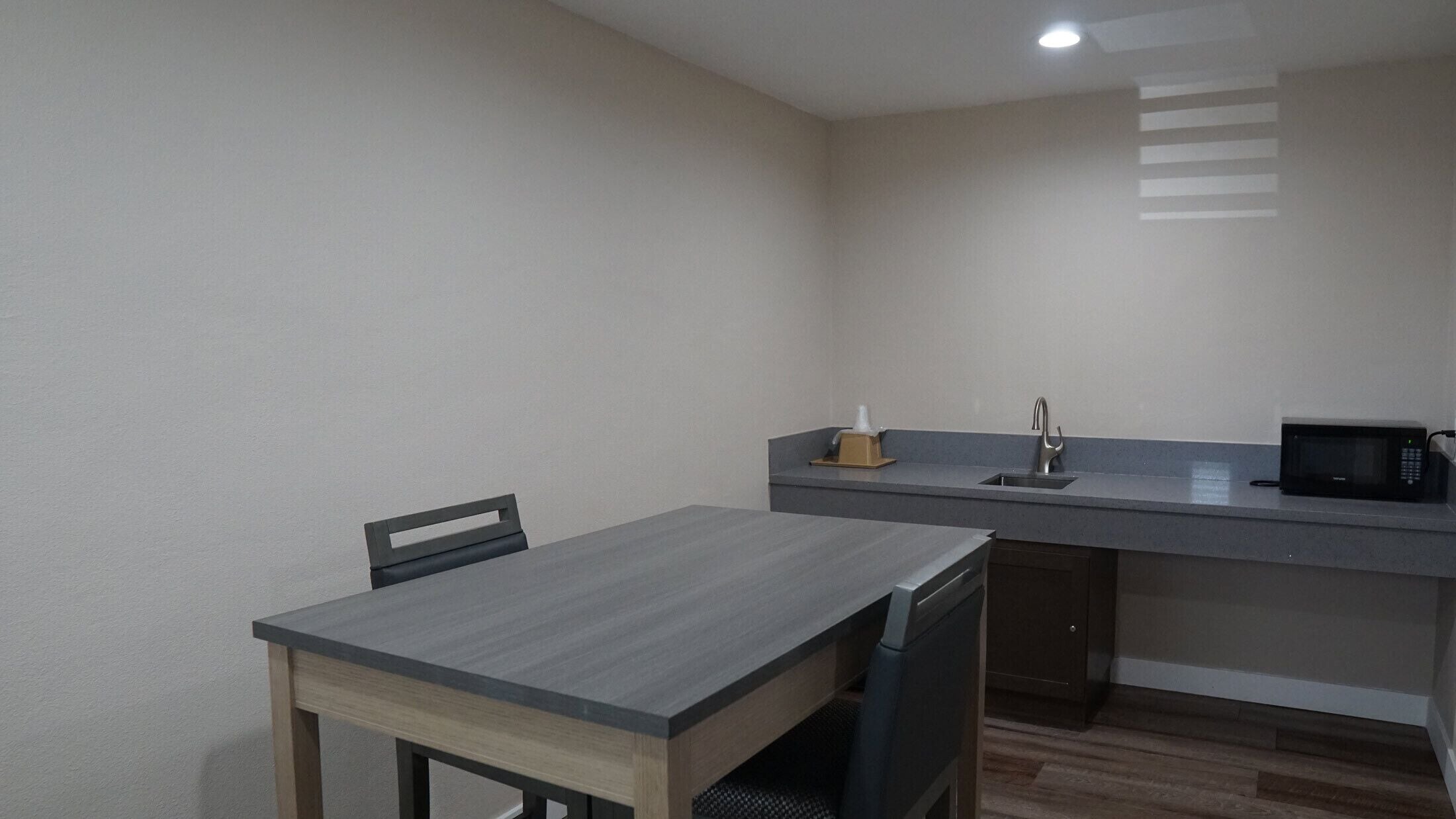 A compact kitchen with a dining table and chairs, a microwave, and a sink.