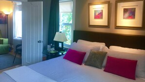 Ein Hotelzimmer mit einem großen Bett, einem Nachttisch, einer Lampe, einem Sessel und zwei gerahmten Bildern an der Wand.