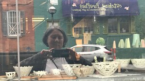 Ein Schaufenster mit Korbwägelchen und einem draußen stehenden Auto.