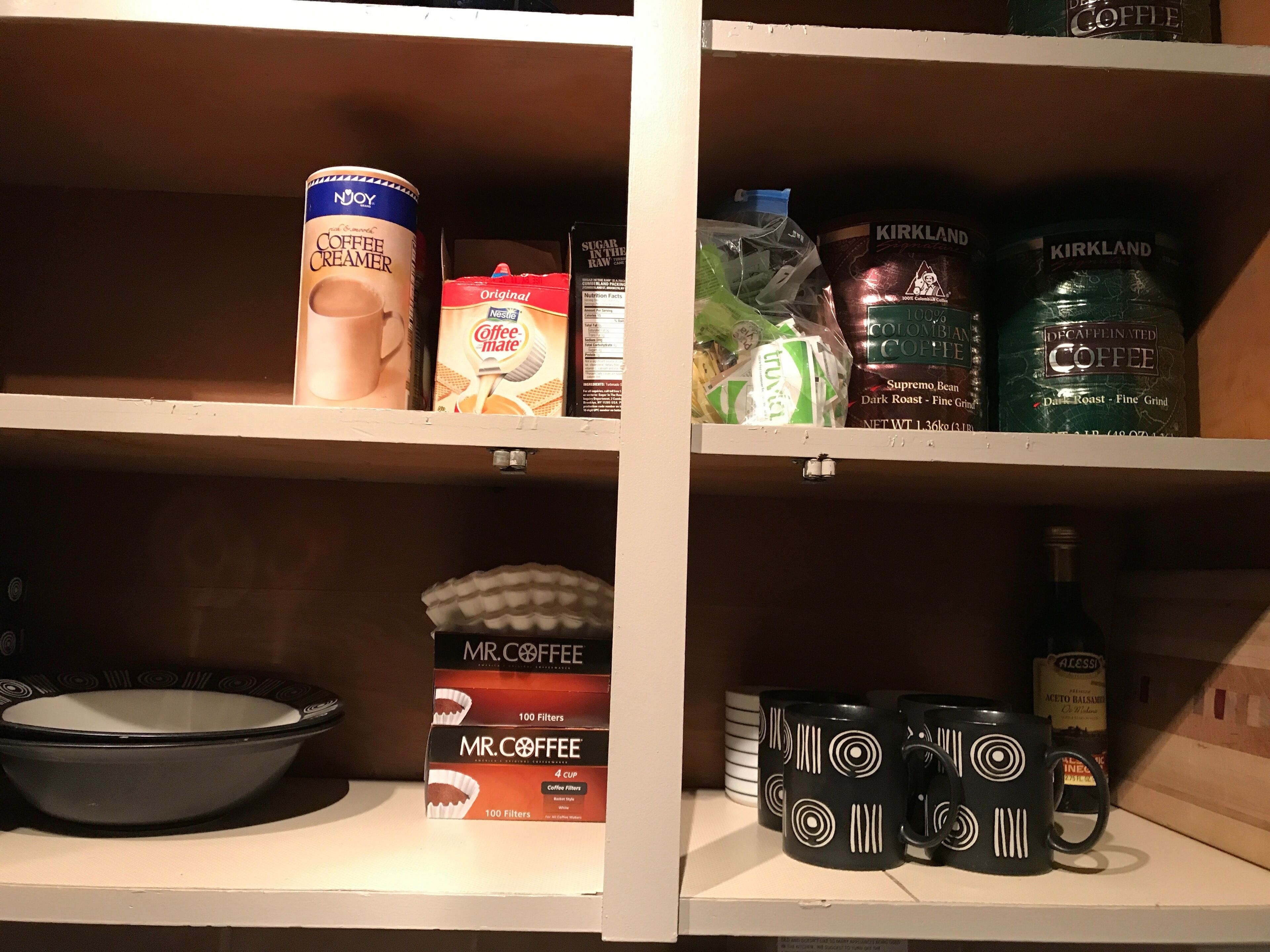 Une étagère contenant divers produits liés au café, notamment du café en poudre, des filtres à café et des tasses à café.