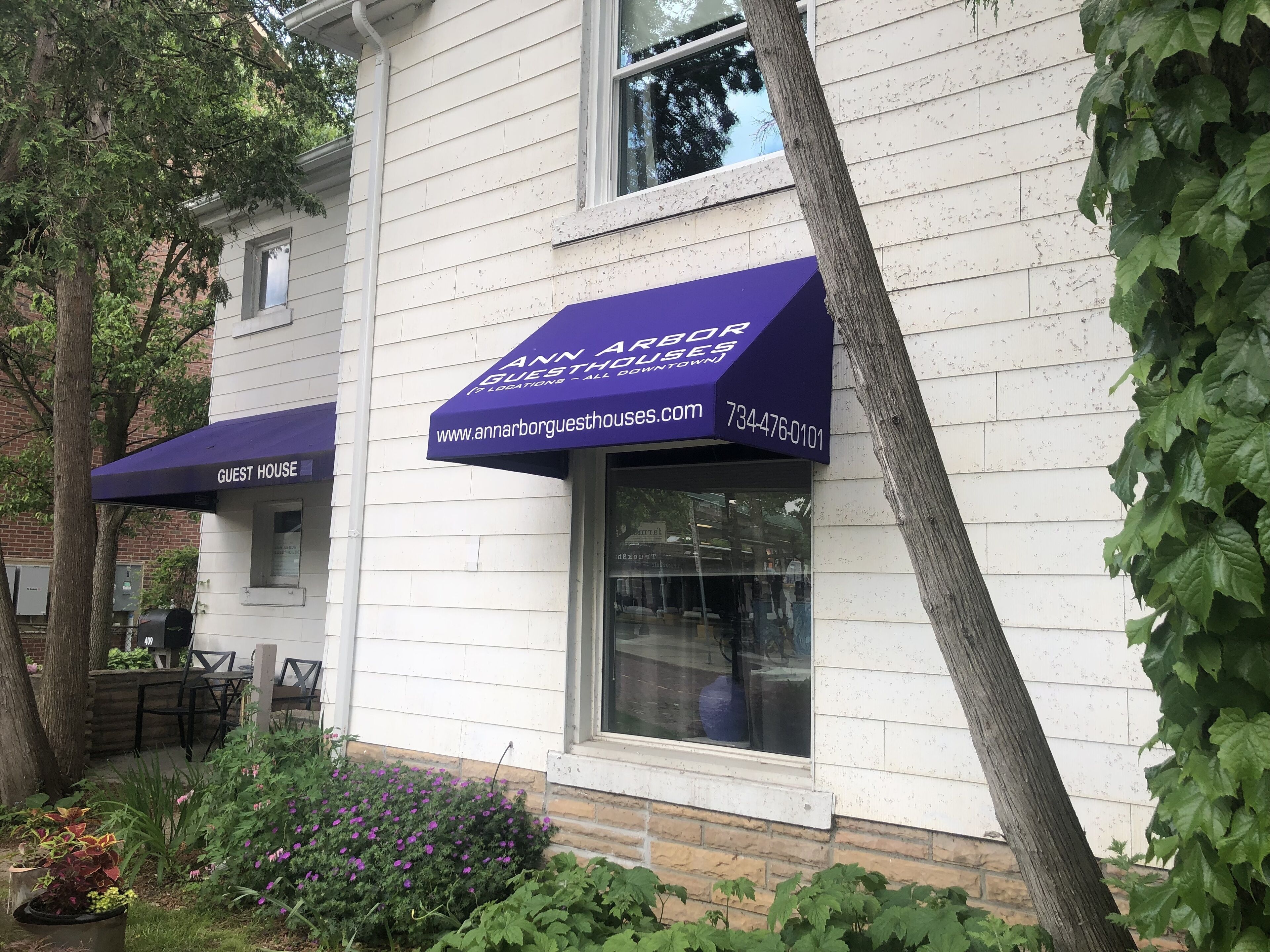Un edificio bianco con un tendone viola con la scritta 'Ann Arbor Guesthouses' e un indirizzo web.