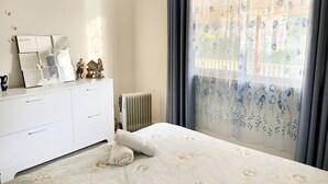 A bedroom with a bed, a dresser, a mirror, and a window with curtains. - Bright & Beautiful Home on the Hills! (Kelmscott)