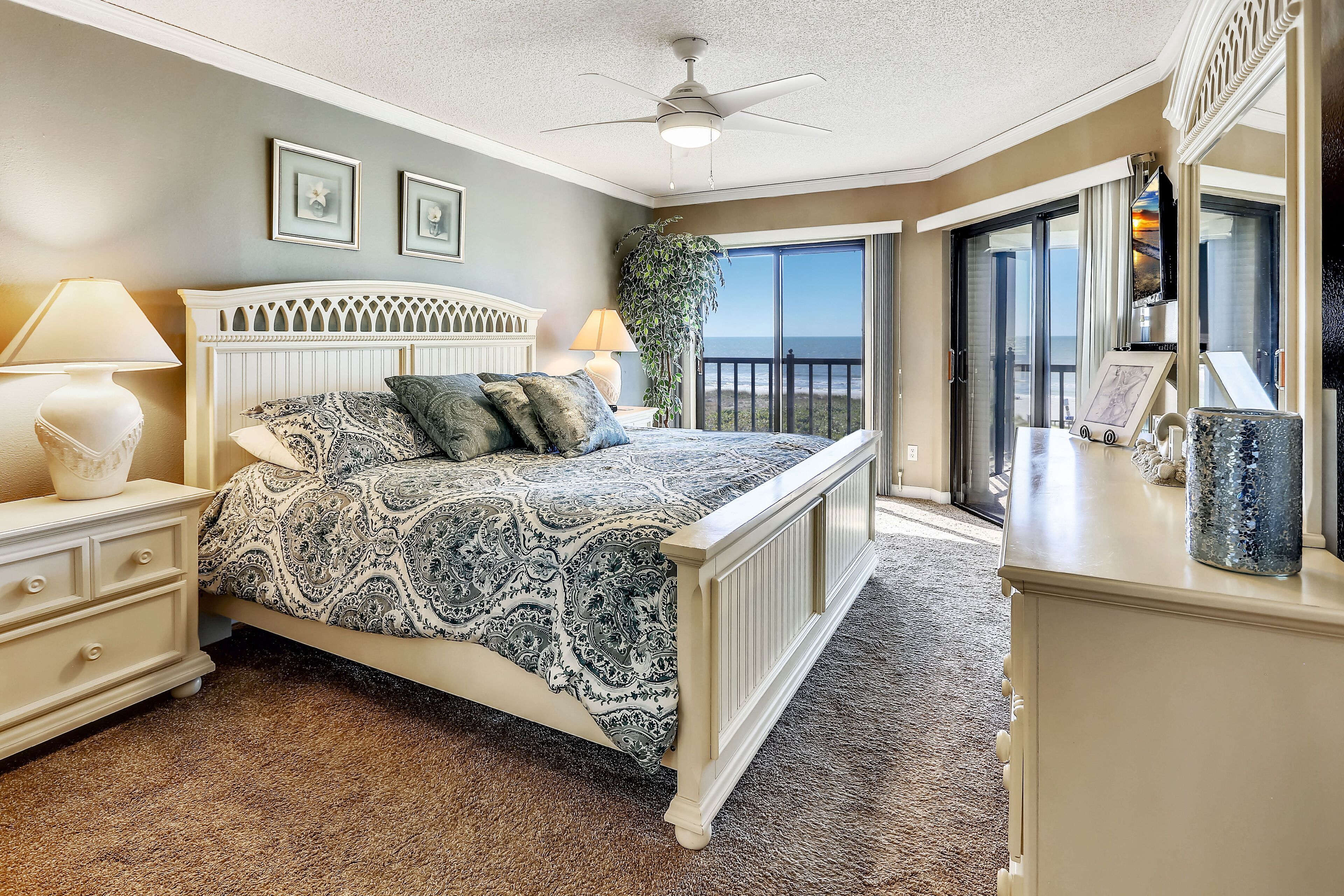 A bedroom with a bed, nightstand, lamp, and a view of the outdoors through a sliding glass door.