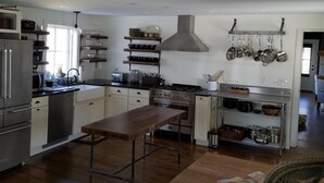 A modern kitchen with stainless steel appliances, a central island, and a hanging pot rack. - Swim, Kayak,  lawn games. Walk to ice cream. Live Theatre , firepit smores!  (Harrison)