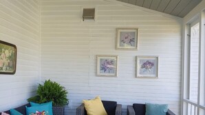 A covered porch with wicker furniture, white flowers, and framed artwork on the walls. - Swim, Kayak,  lawn games. Walk to ice cream. Live Theatre , firepit smores!  (Harrison)