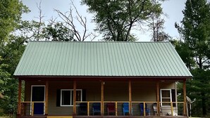 Une petite cabane à un seul étage, avec un toit en métal et une véranda.