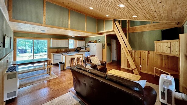 Une cabane spacieuse comprenant une cuisine, un coin repas et un salon confortable avec une cheminée.
