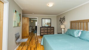 Ein Schlafzimmer mit Bett, Kommode, Stuhl und einem zur anderen Kammer führenden Gang.