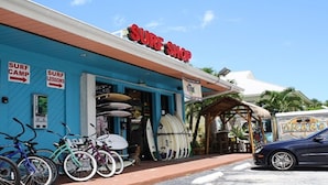 Una tienda de surf con tablas de surf y bicicletas afuera.