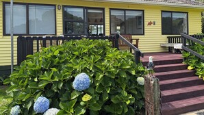 A yellow building with large windows and a porch. - The Yellow Bach 90m to Campbells Beach; kayaks, wifi, Sky, Netflix, sleeps 4 (Campbells Beach)