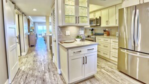 A modern kitchen with stainless steel appliances, white cabinetry, and a central island.