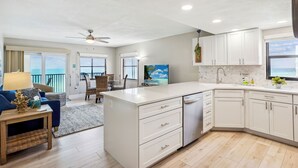 Una cocina moderna con armarios blancos, una isla grande y vista al océano.