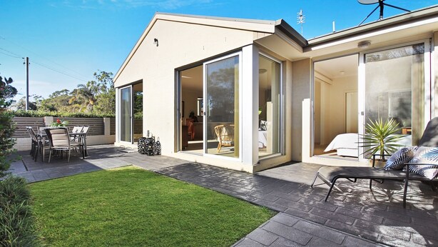 Une maison moderne dotée d’un patio, d’un coin repas et d’un salon avec un canapé et une plante.