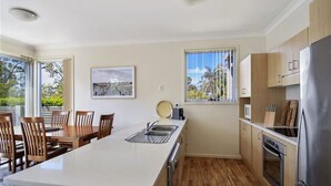 Une cuisine moderne dotée d’un îlot central, de meubles en bois et d’une grande fenêtre offrant une vue sur l’extérieur.
