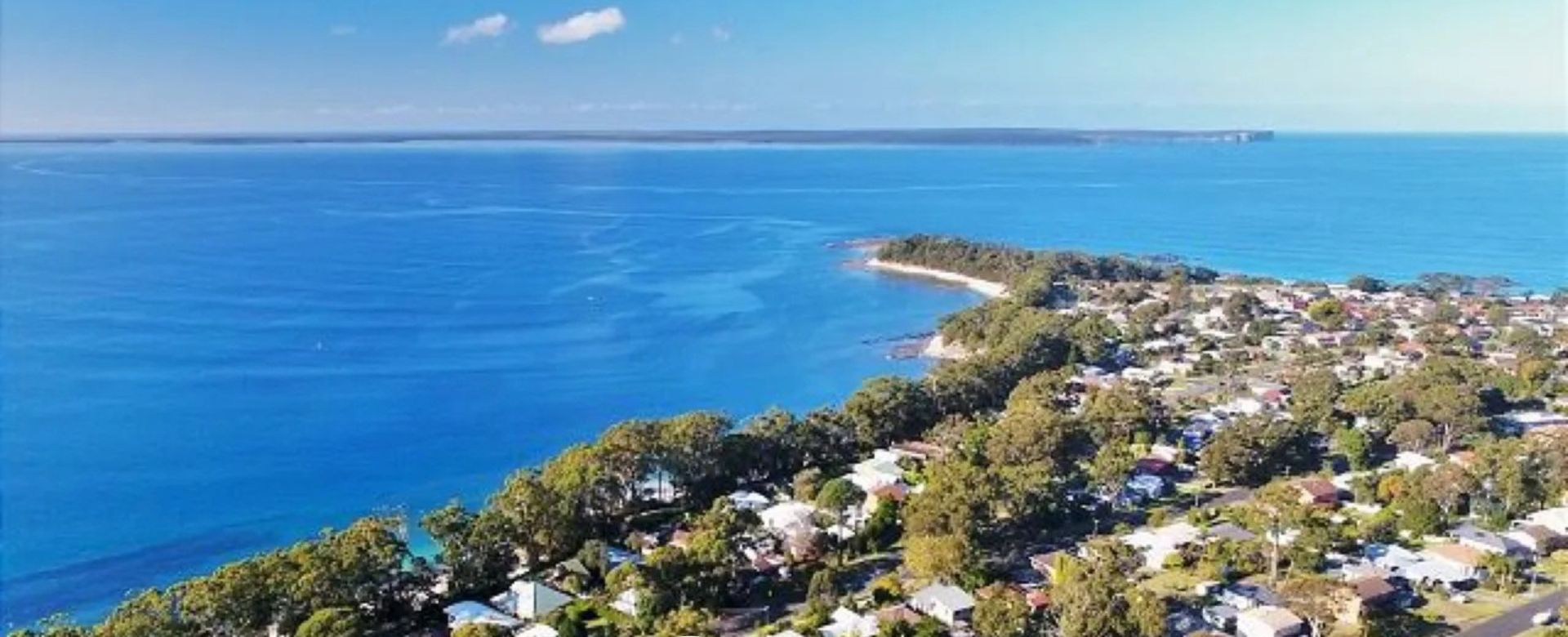 Vista aérea de una zona residencial costera con casas, calles y una playa.