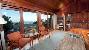 A spacious living area with large windows, wooden flooring, and a cozy seating arrangement. - Stunning Ranch Home with Ocean Views (Carmel)