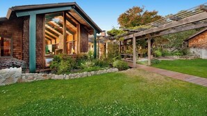A modern house with a large glass window, a wooden pergola, and a well-maintained garden. - Stunning Ranch Home with Ocean Views (Carmel)
