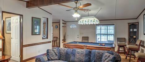 A living room with a pool table, a sofa, and a ceiling fan.