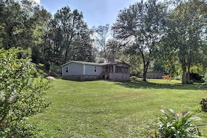 A house with a covered porch, surrounded by a well-maintained lawn and trees.