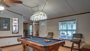 A pool table with balls, a ceiling fan, and a chandelier. - Ooltewah Cabin w/ Grill, Pool Table & Porch! (Ooltewah)