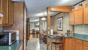 A kitchen with wooden cabinets, a microwave, a dining area with chairs and a table, and a chandelier. - Ooltewah Cabin w/ Grill, Pool Table & Porch! (Ooltewah)