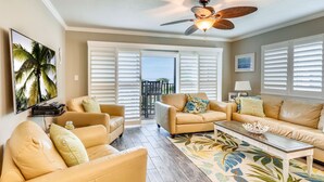 A living room with beige sofas, a coffee table, and a ceiling fan.