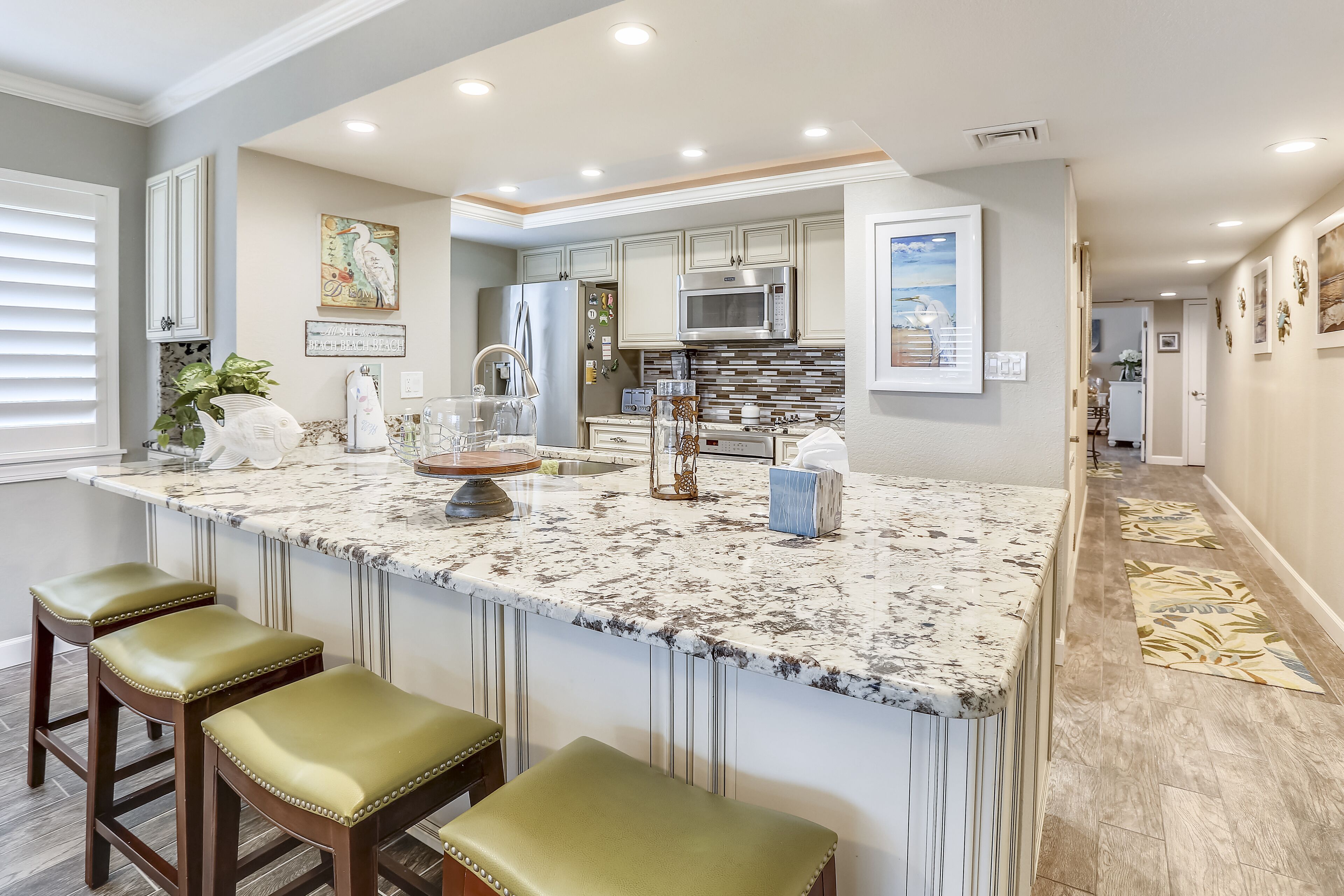 A kitchen with a large island, bar stools, and a microwave.