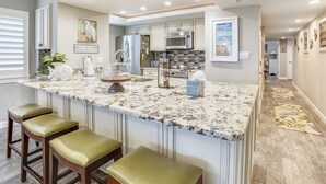A kitchen with a large island, bar stools, and a microwave.