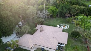 A house with a large, sloped roof surrounded by dense greenery. - Beautiful Vacation Home Across from Lake Okeechobee (Okeechobee)