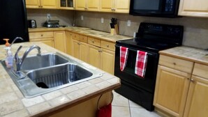 A kitchen with wooden cabinets, a stainless steel sink, a black stove, and a microwave. - Beautiful Vacation Home Across from Lake Okeechobee (Okeechobee)