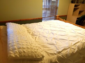 Un lit bien fait, avec une couette blanche et un coussin décoratif.