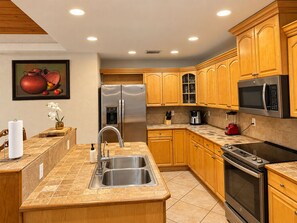 A modern kitchen with stainless steel appliances, wooden cabinets, and a tiled backsplash. - Beautiful Vacation Home Across from Lake Okeechobee (Okeechobee)