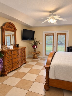 A bedroom with a bed, dresser, television, and a ceiling fan. - Beautiful Vacation Home Across from Lake Okeechobee (Okeechobee)