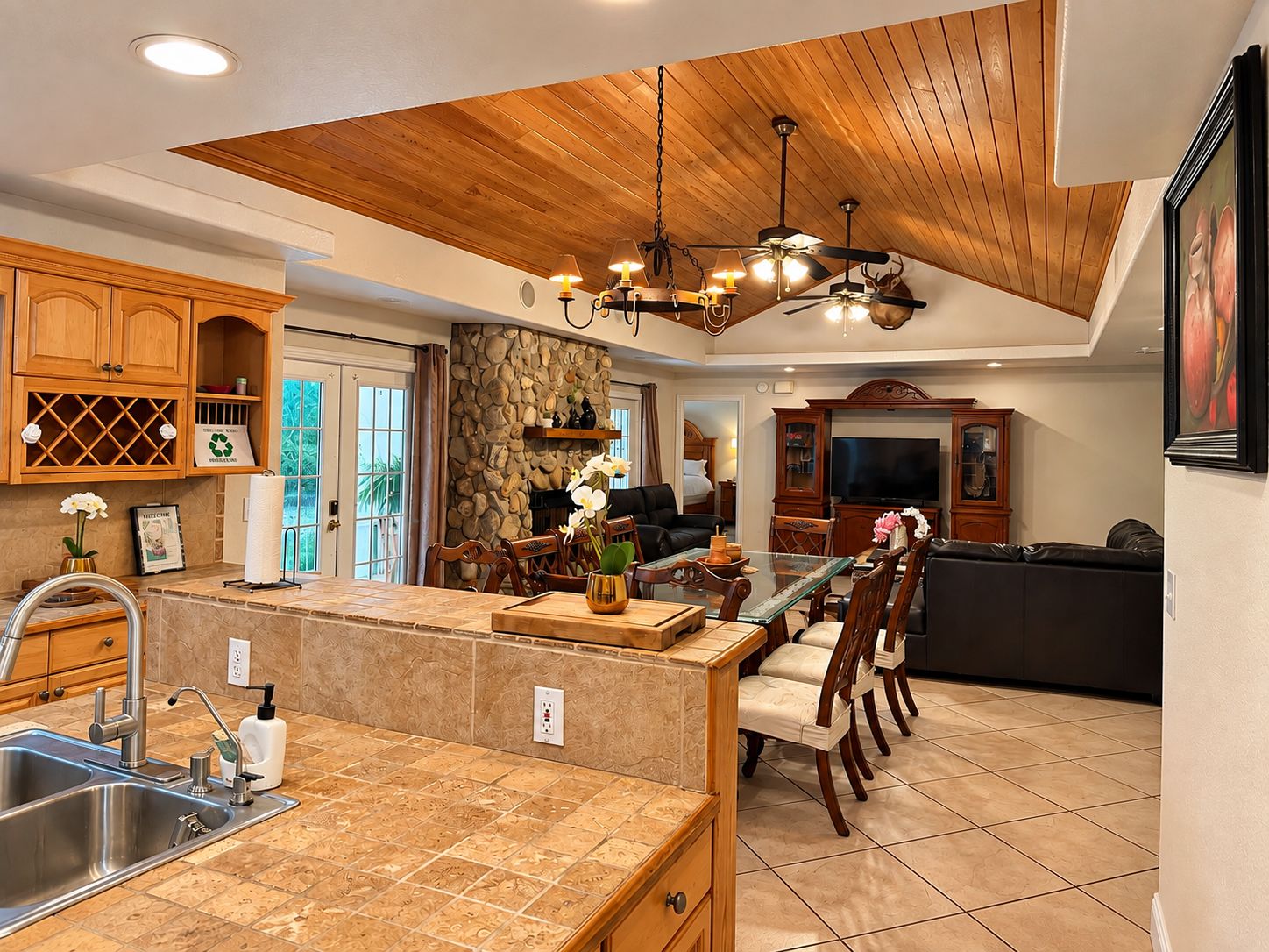Une cuisine moderne avec un mur de crédence en pierre, des armoires en bois et un grand îlot central doté de tabourets de bar.