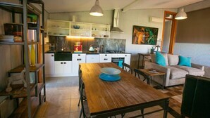 Une cuisine moderne avec des meubles blancs, une table à manger en bois et un canapé agrémenté de coussins turquoise.