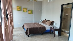 A bedroom with a bed, bedside tables, a nightstand, a shower, and wall art. - Affordable Furnished 2-Story Ocean view Townhouse (San Jacinto)