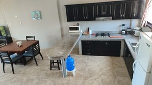 A kitchen with a granite countertop, black cabinets, a stove, and a refrigerator. - Affordable Furnished 2-Story Ocean view Townhouse (San Jacinto)