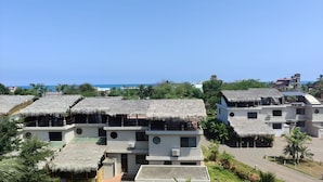 A resort with thatched-roof buildings, a paved walkway, and a view of the ocean. - Affordable Furnished 2-Story Ocean view Townhouse (San Jacinto)