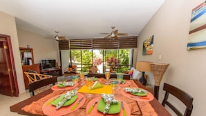 A dining area with a table set for six, chairs, ceiling fans, and a view of greenery outside. - Beach Townhouse with Private Parking (San Jacinto)