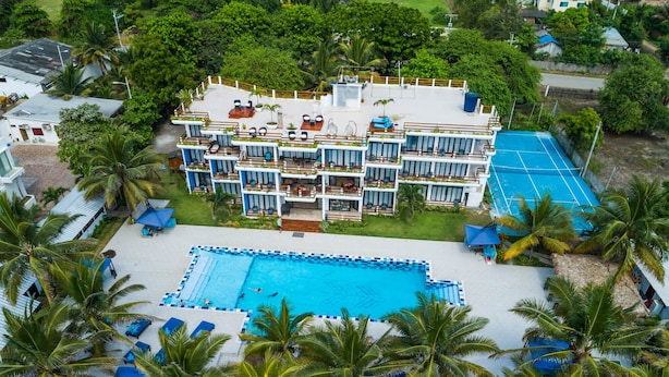 A resort with a large pool, multiple balconies, and palm trees. - Beach Townhouse with Private Parking (San Jacinto)