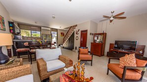A spacious living room with a TV, comfortable seating, a dining area, and a staircase leading to another level. - Beach Townhouse with Private Parking (San Jacinto)