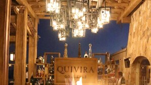Un espace bar agrémenté d’un foyer, de poutres en bois au plafond et d’une enseigne indiquant « QUIVIRA GOLF CLUB ».