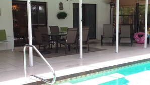 Ett takförsett utomhusområde med en pool, sittplatser och en takfläkt.