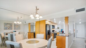 Eine moderne Küche mit Holzausstattung, einer zentralen Kochinsel und einem Essbereich mit rundem Tisch und Stühlen.