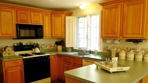 Une cuisine avec des meubles de rangement en bois, un micro-ondes noir, une cuisinière et un évier.
